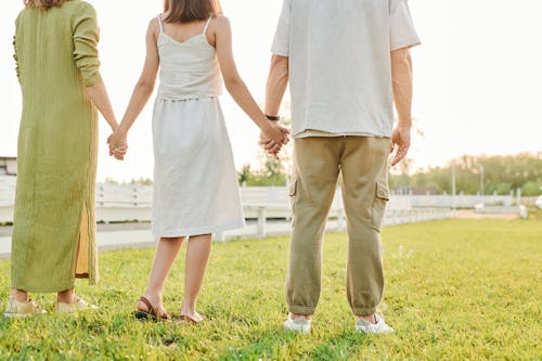 Free Three People Standing Hand in Hand on Grass Field  Stock Photo