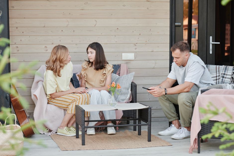 A family enjoying a relaxing day on their patio, engaging with digital devices.