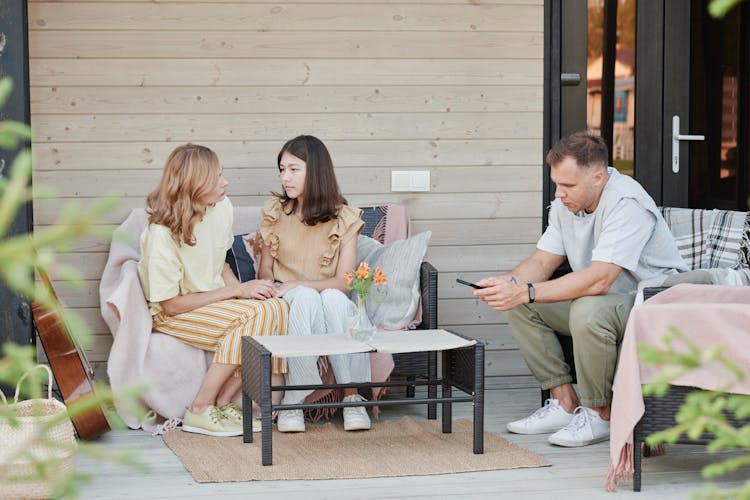 Family Resting On Seats On Patio