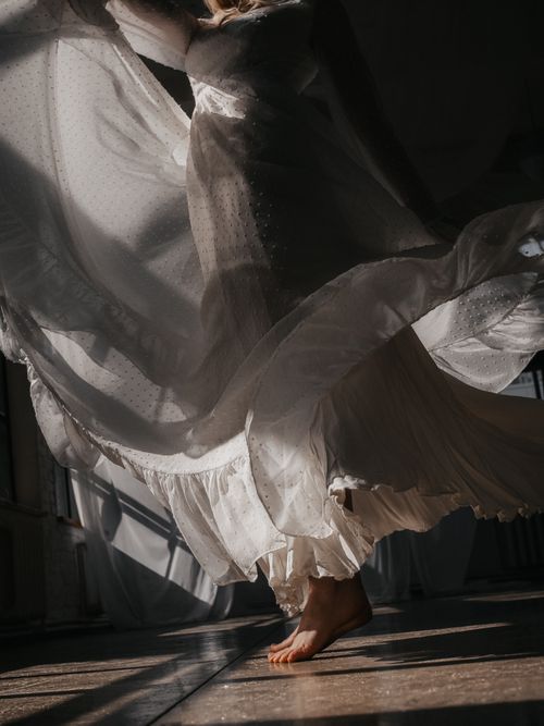 Free A graceful dance captured in a white flowing dress with dramatic shadows. Stock Photo