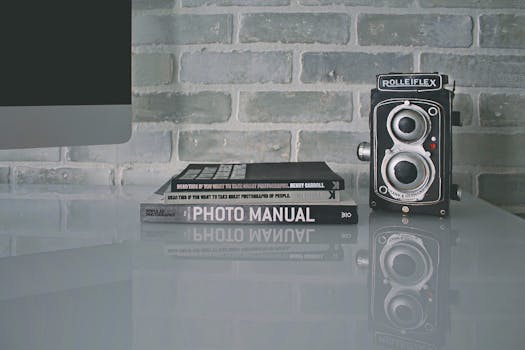 A vintage Rolleiflex camera beside photography books on a reflective surface indoors.