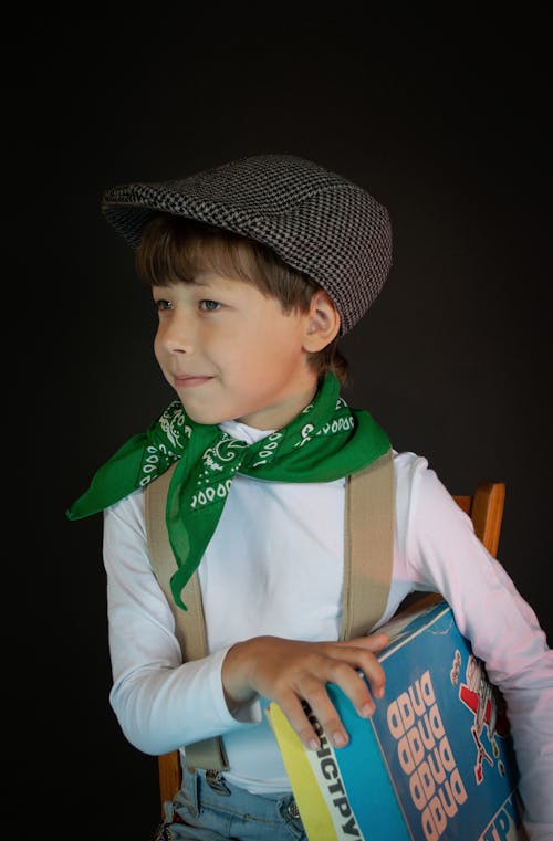 Close-Up Photo of a Boy in a Black Flat Cap Holding a Board Game