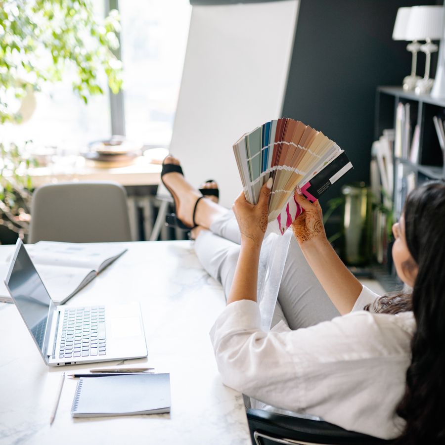 Designer with feet up at a marble desk, laptop and colour swatches in a bright studio — photo by Yan Krukau on Pexels