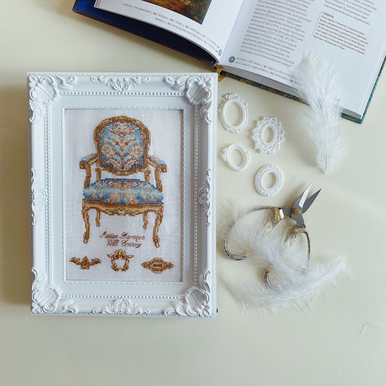 Cross Stitched Image Of Chair In White Ornate Frame