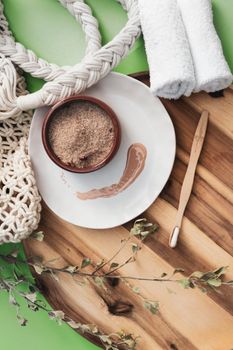 Flat lay of natural spa items including towels and brown sugar scrub on a wooden tray.