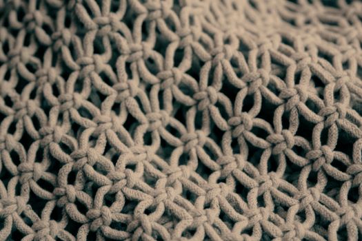 Detailed close-up of a handmade knitted pattern showcasing intricate weaving and knots.