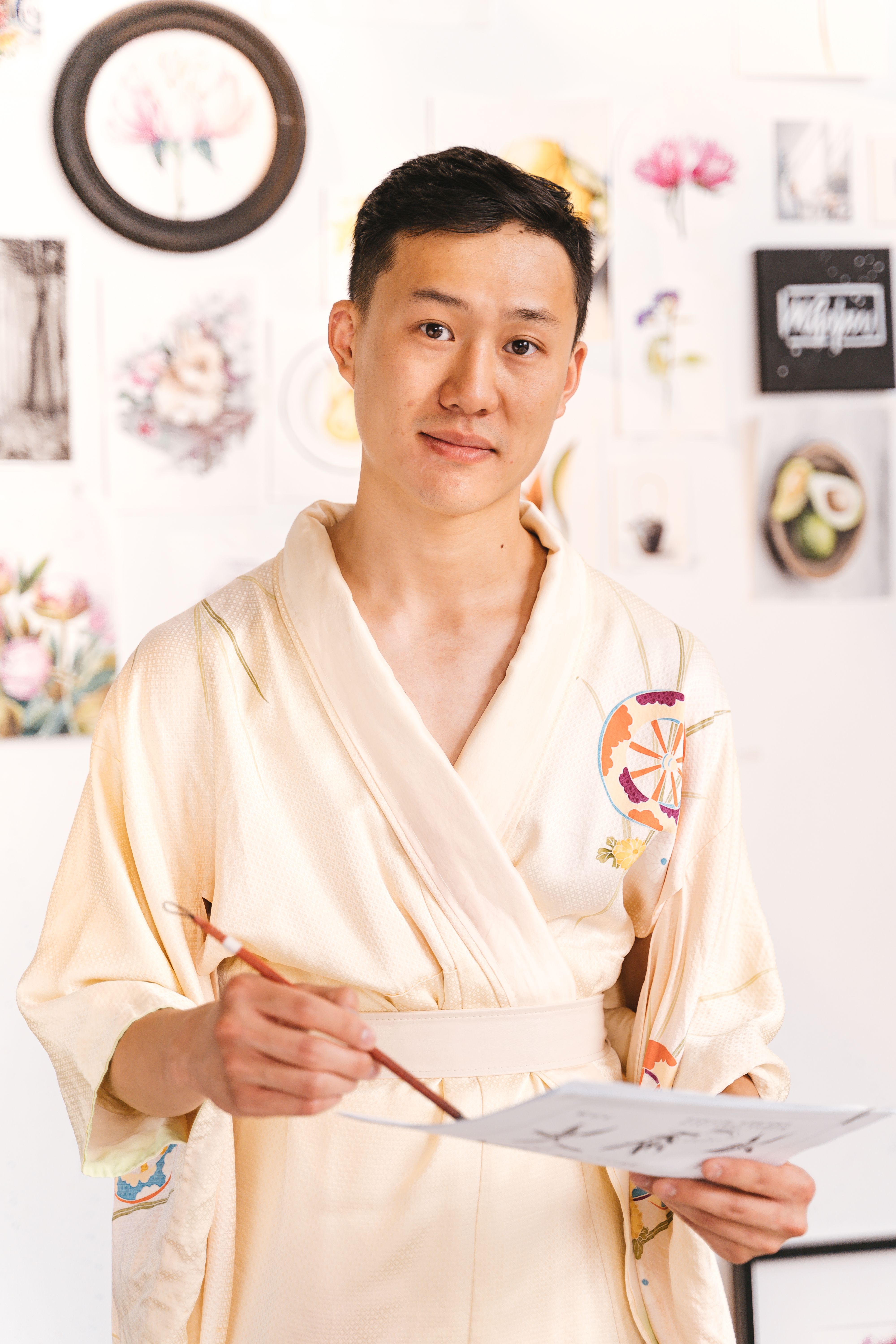 A creative Asian adult painting with a brush in an artistic studio setting.