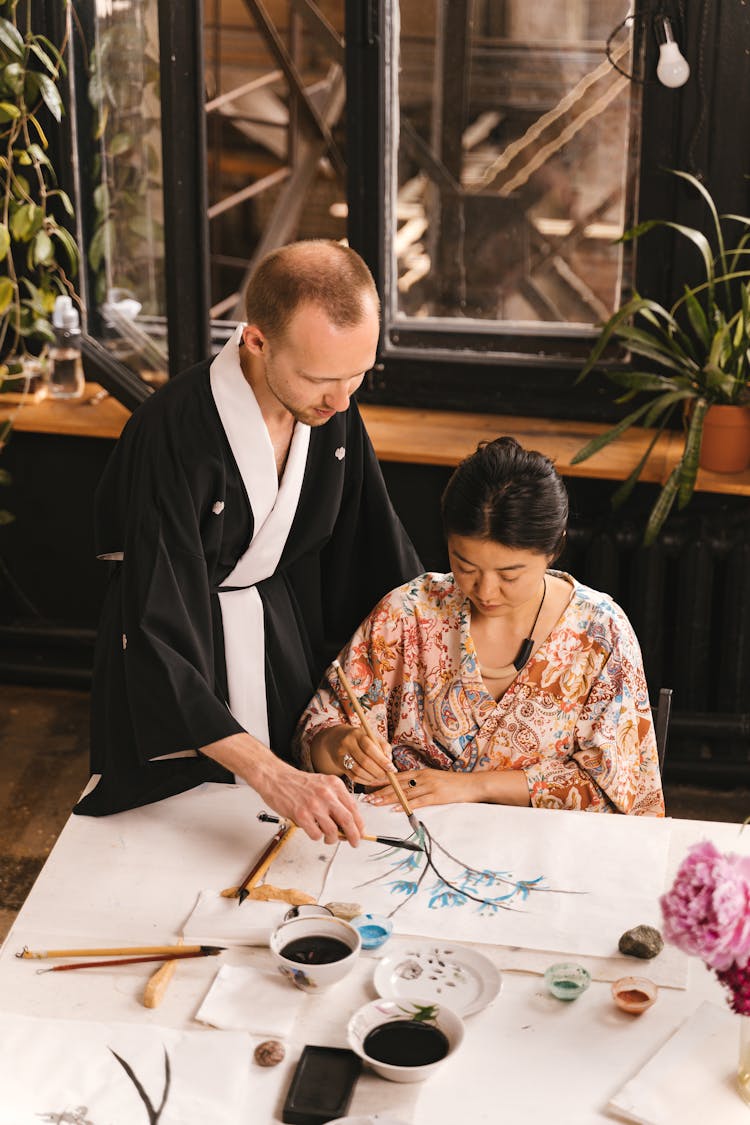 Man Teaching Woman Traditional Painting Technique