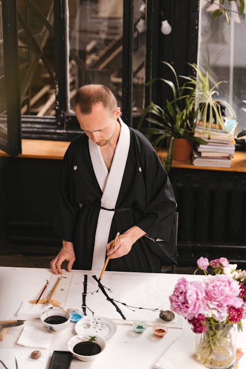 A Man wearing Robe doing Painting 