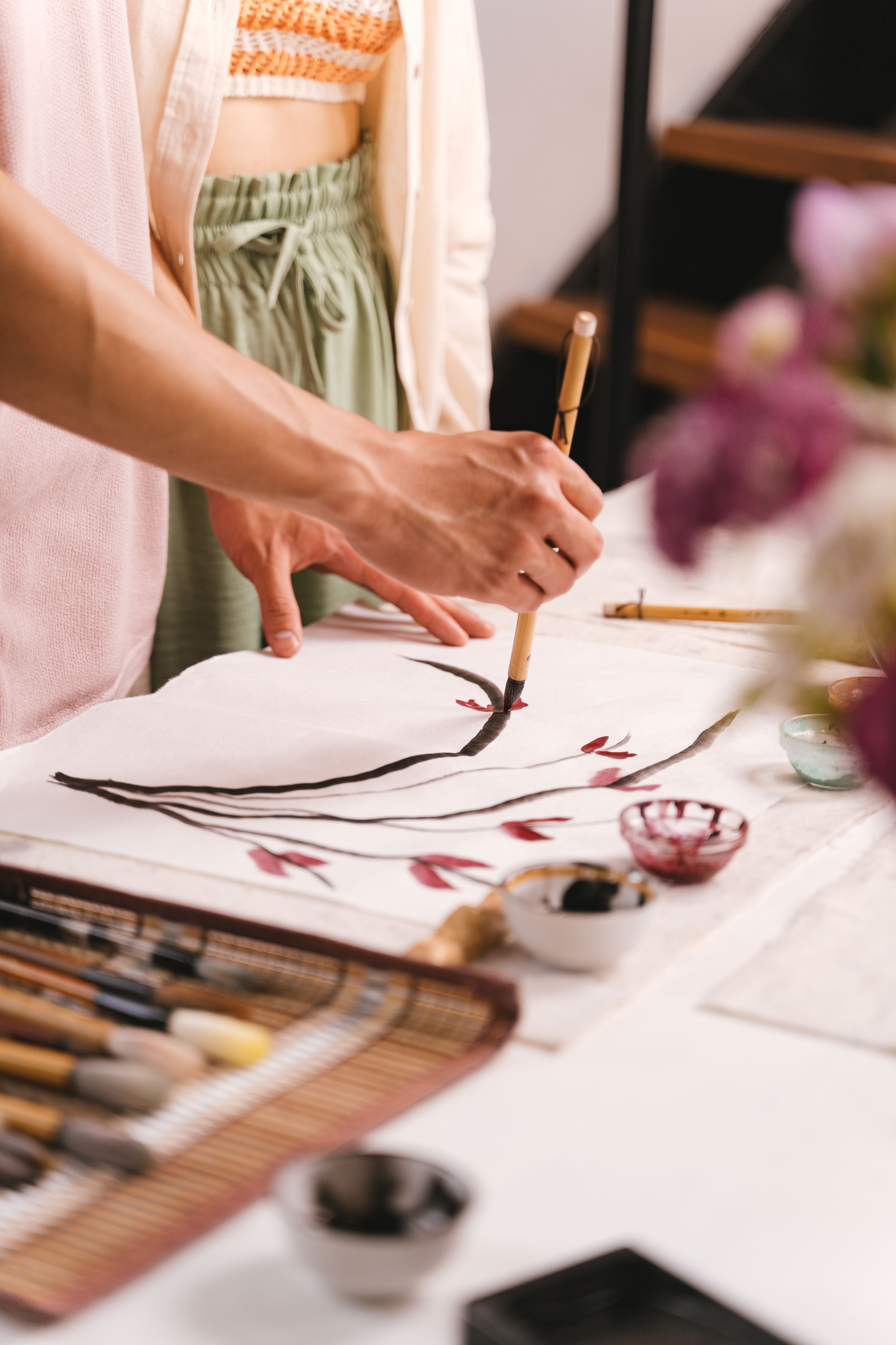 Hands delicately painting with ink and brush, focusing on artistic expression and creativity.