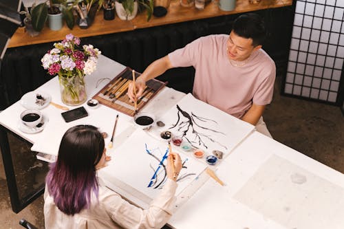 Woman in White Crew Neck T-shirt Painting on White Table