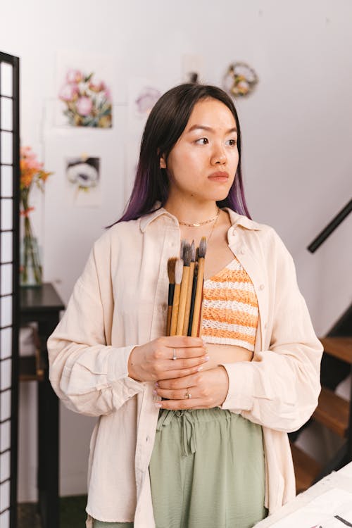Woman Holding Paintbrushes while Standing