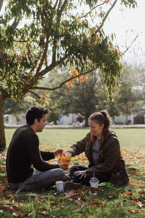 Man and Woman Sitting on Grass Field