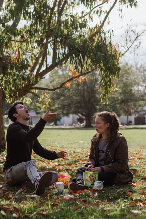 A Couple Sitting on Grass Eating Junk Food