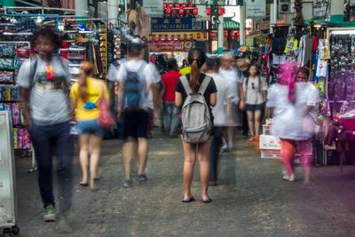 A crowded city street with people walking, blurred in motion