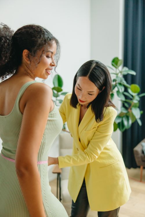 Free Two women measuring waistline indoors, focusing on fitness and fashion. Stock Photo