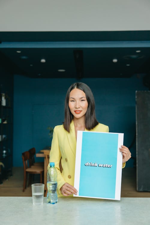 Woman in Yellow Long Sleeve Shirt Holding Blue Paper