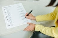 Person Holding Black Pen Writing on White Paper