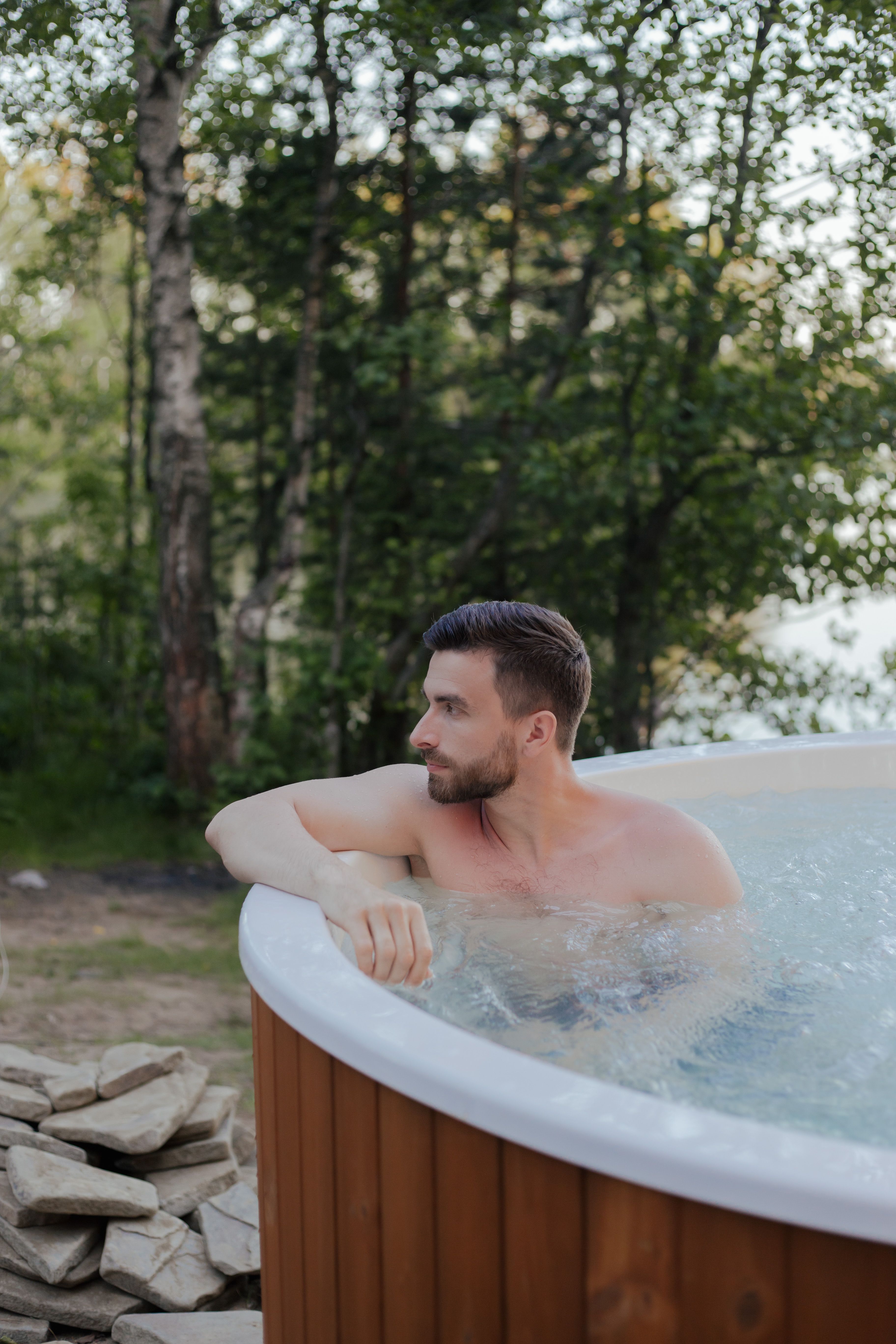 Man relaxing in an outdoor wooden hot tub