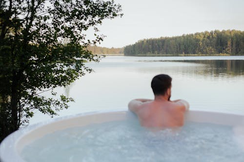 Free Back View of a Shirtless Man Relaxing in a Jacuzzi Stock Photo