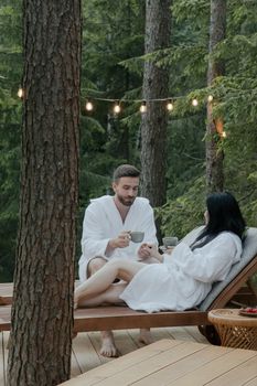 A serene moment shared by a couple enjoying beverages outdoors in a forest setting.