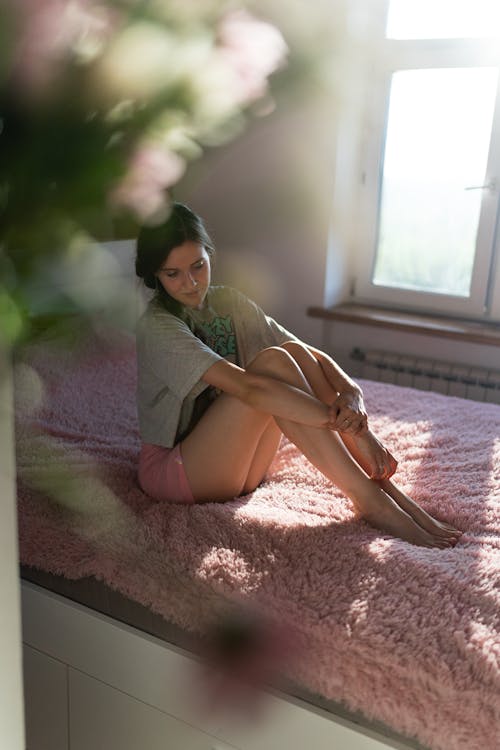 Free A Woman Sitting on a Bed Stock Photo