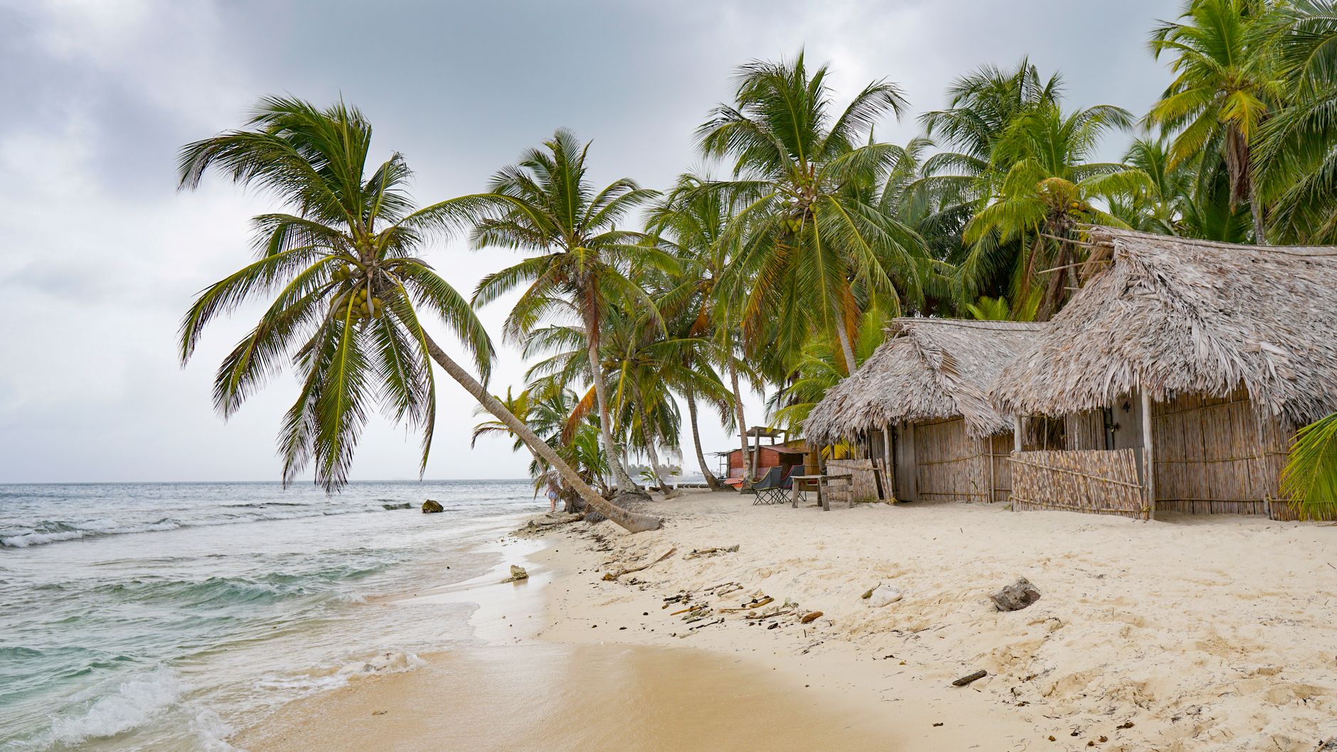 Overwater thatch huts on a pristine Caribbean beach in Guna Yala, Panama — a reminder of the country's extraordinary coastal diversity accessible from the Pacific Riviera.