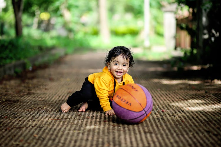 Boy Sitting On The Floor Beside A Ball