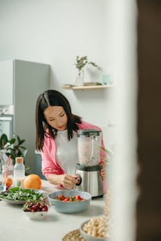 Woman blending fresh fruits and greens for a healthy smoothie.