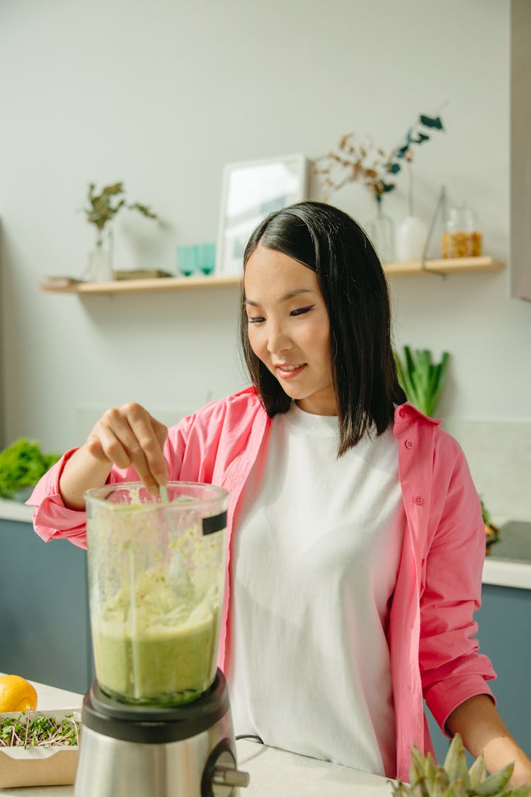 Asian Woman Making Green Smoothie At Kitchen