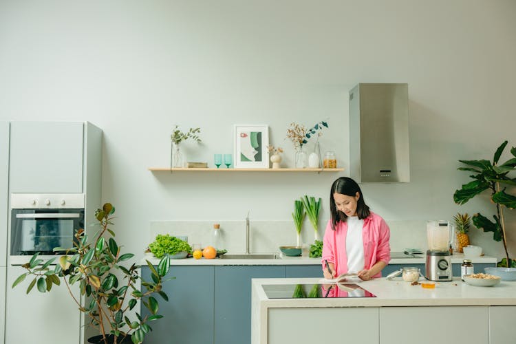 Woman In The Kitchen Writing On A Notebook 