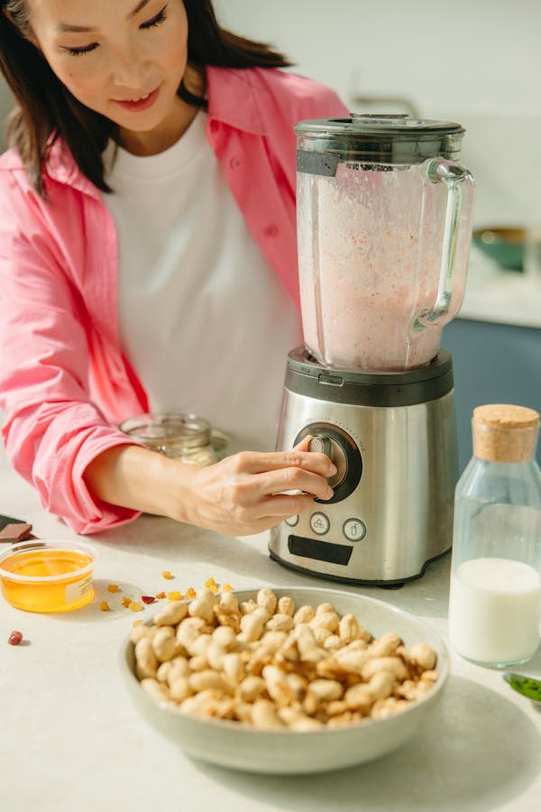 Femme préparant un smoothie santé dans un blender en cuisine moderne