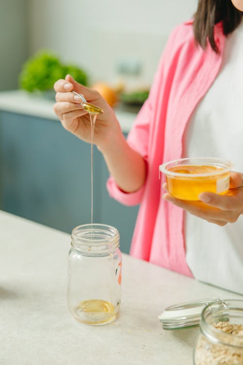 A Person Putting Honey in Glass Jar