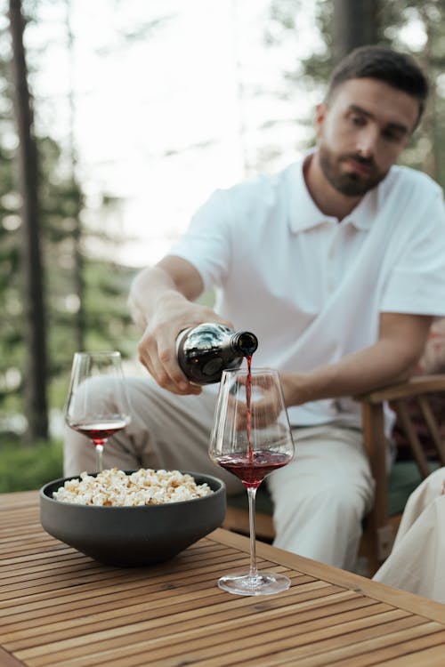 Man in White Polo Shirt Pouring Red Wine in Clear Wine Glass