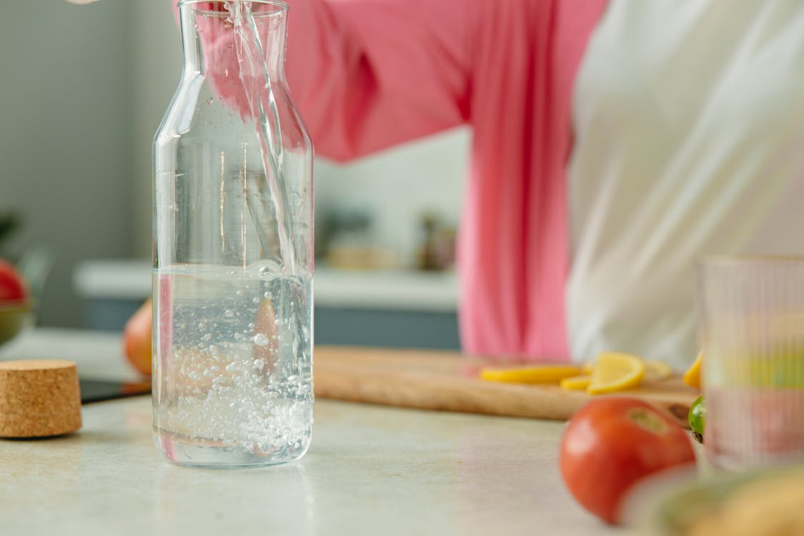 Free A Person Pouring Water on a Clear Pitcher Stock Photo