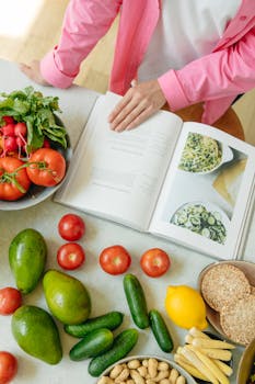 Overhead view of fresh vegetables and an open cookbook on a kitchen counter.