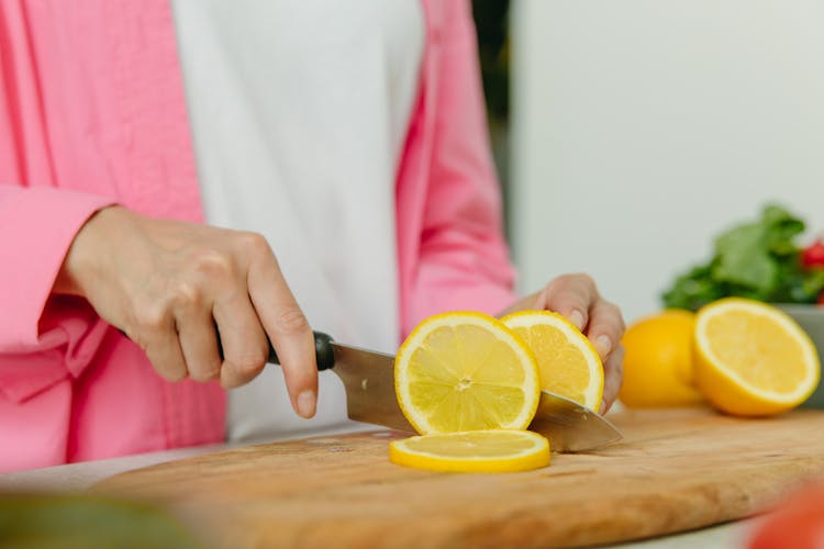 Person Holding Knife Slicing Lemon