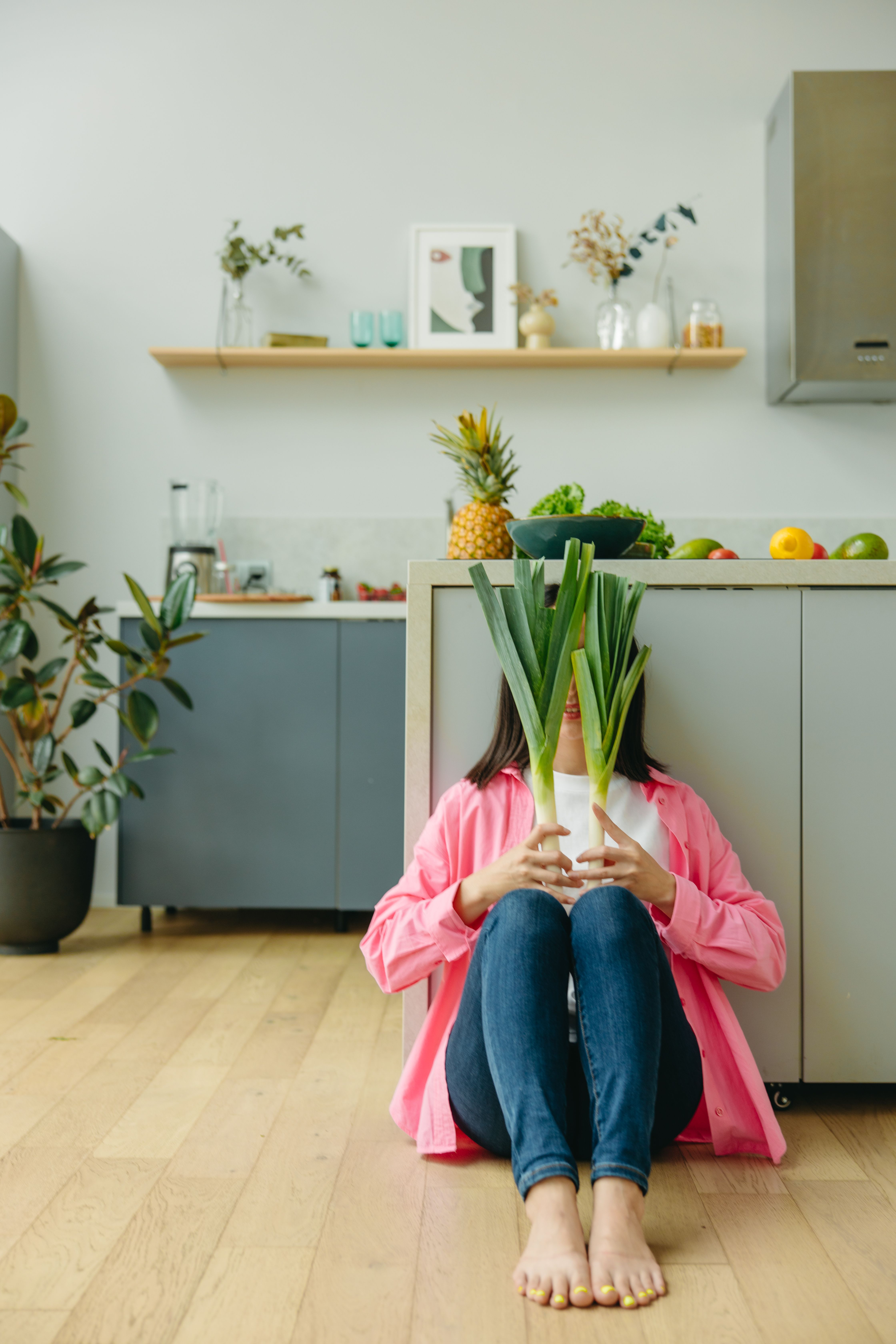 Unrecognizable woman sitting with fresh leeks in a cozy home kitchen.