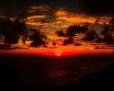 日落令人惊叹，色彩鲜艳，地平线上的云层引人注目