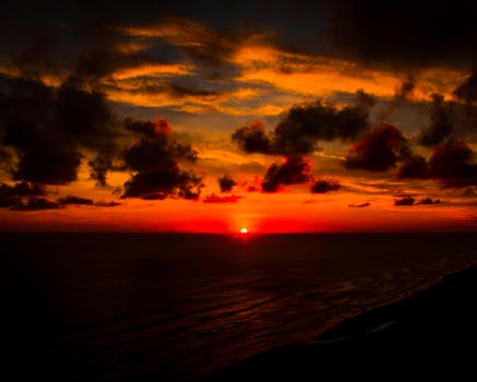 日落令人惊叹，色彩鲜艳，地平线上的云层引人注目