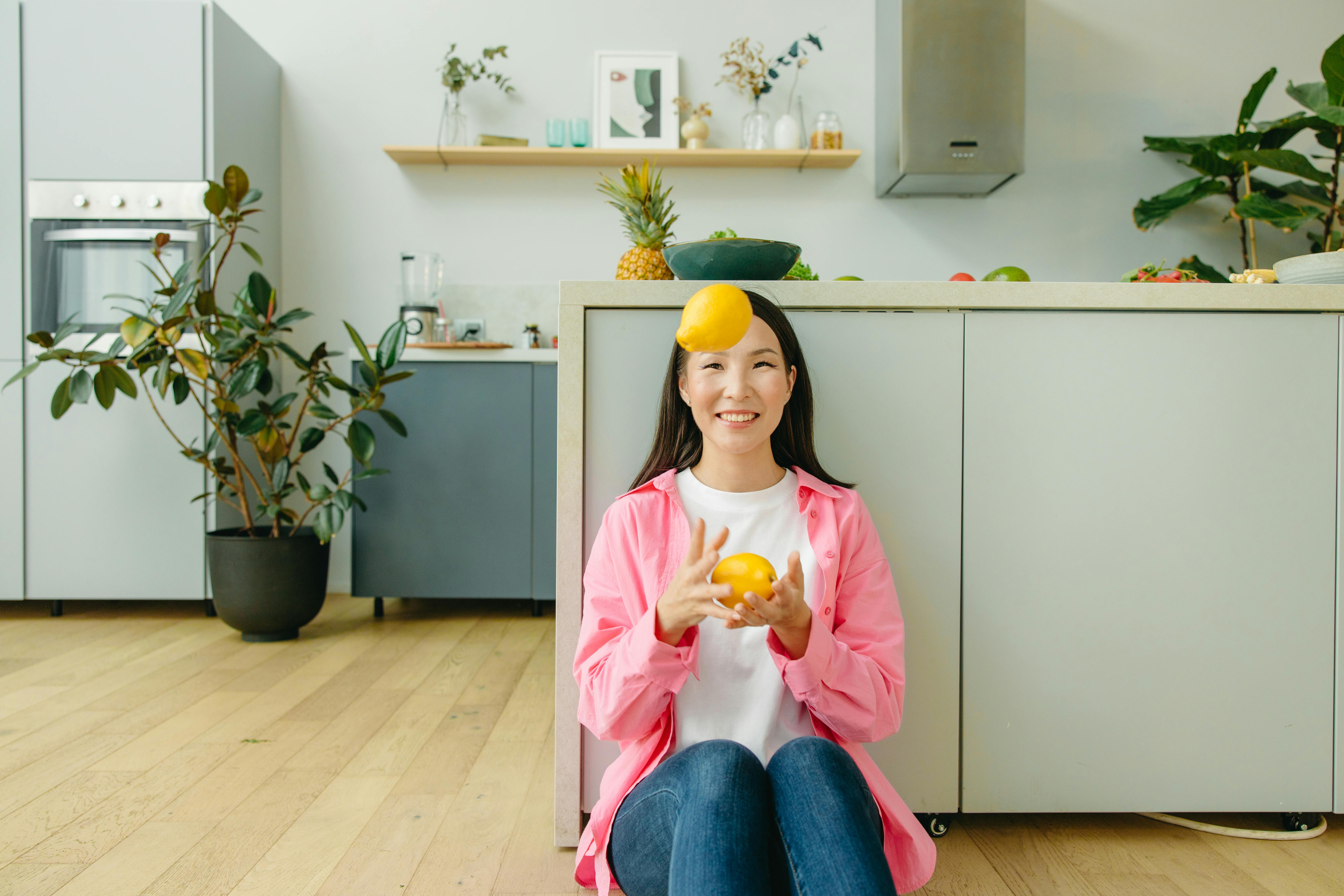 A Woman Sitting on the Floor Juggling the Lemons she is Holding · Free