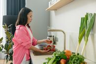 Girl in Pink Shirt Standing in Front of Table With Fruits