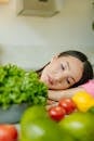 Woman in Pink Shirt Lying on Bed With Green and Yellow Fruits