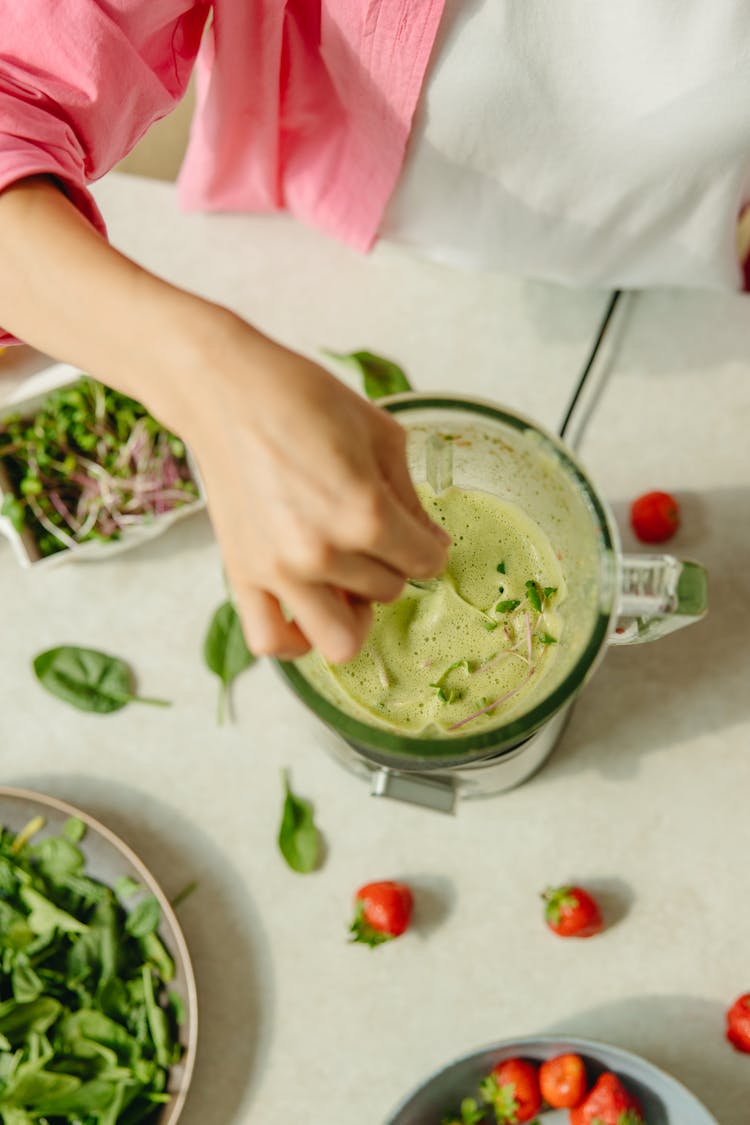 A Hand Putting Leaves On A Blender With Shake