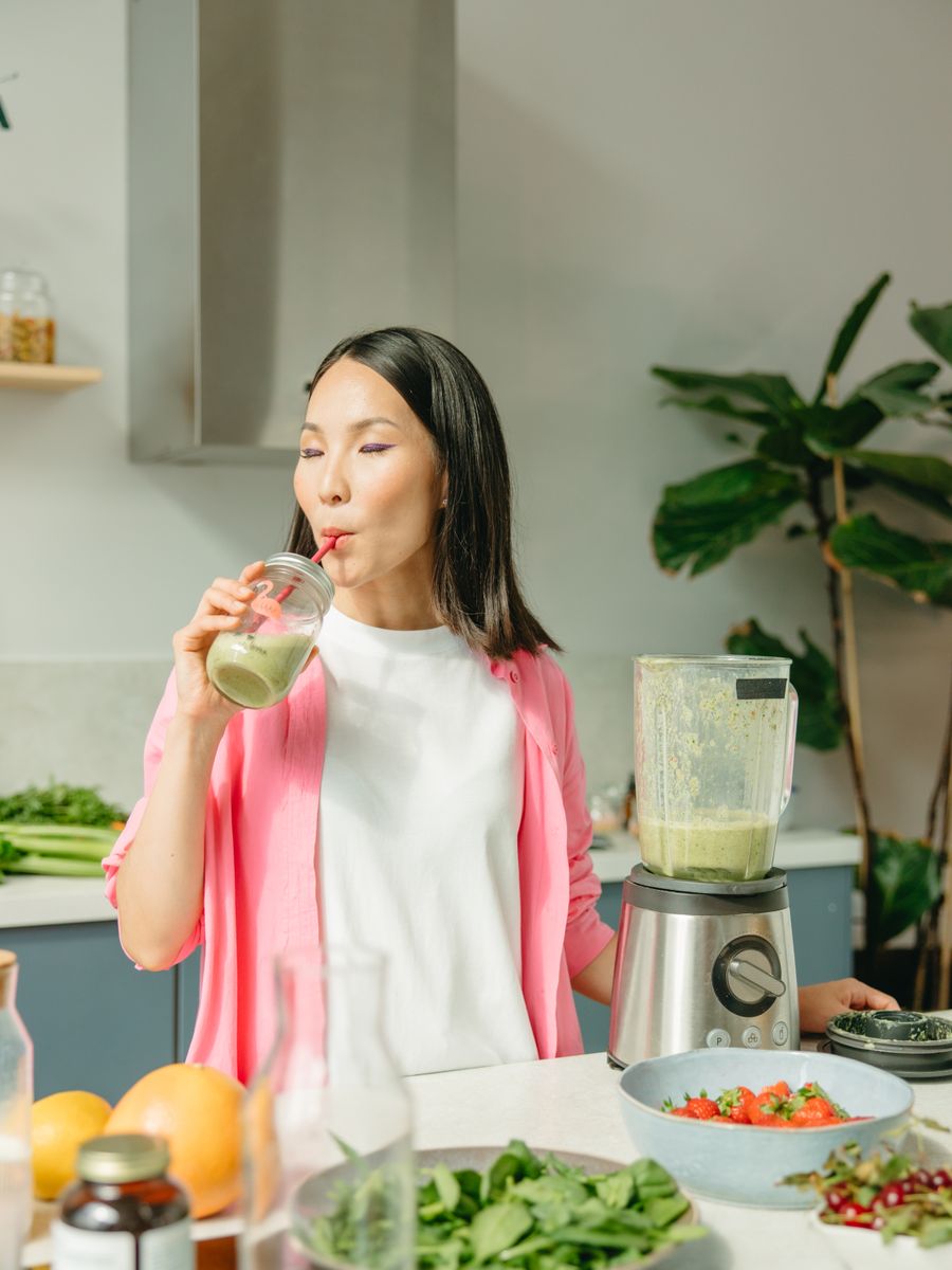Woman drinking a wellness smoothie in a bright kitchen