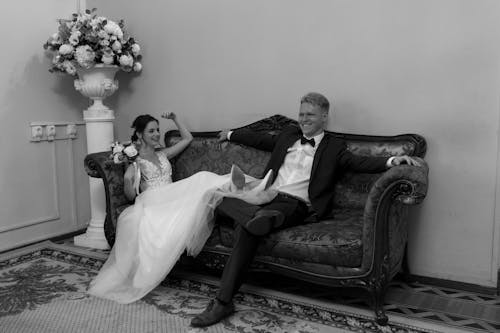Monochrome Photo of a Groom and a Bride Sitting on a Sofa