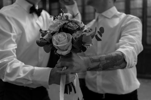 Grayscale Photo of a Couple Holding a Bouquet of Flowers