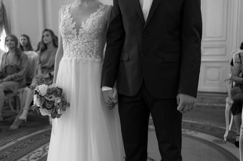 Grayscale Photo of a Bride and Groom Holding Hands