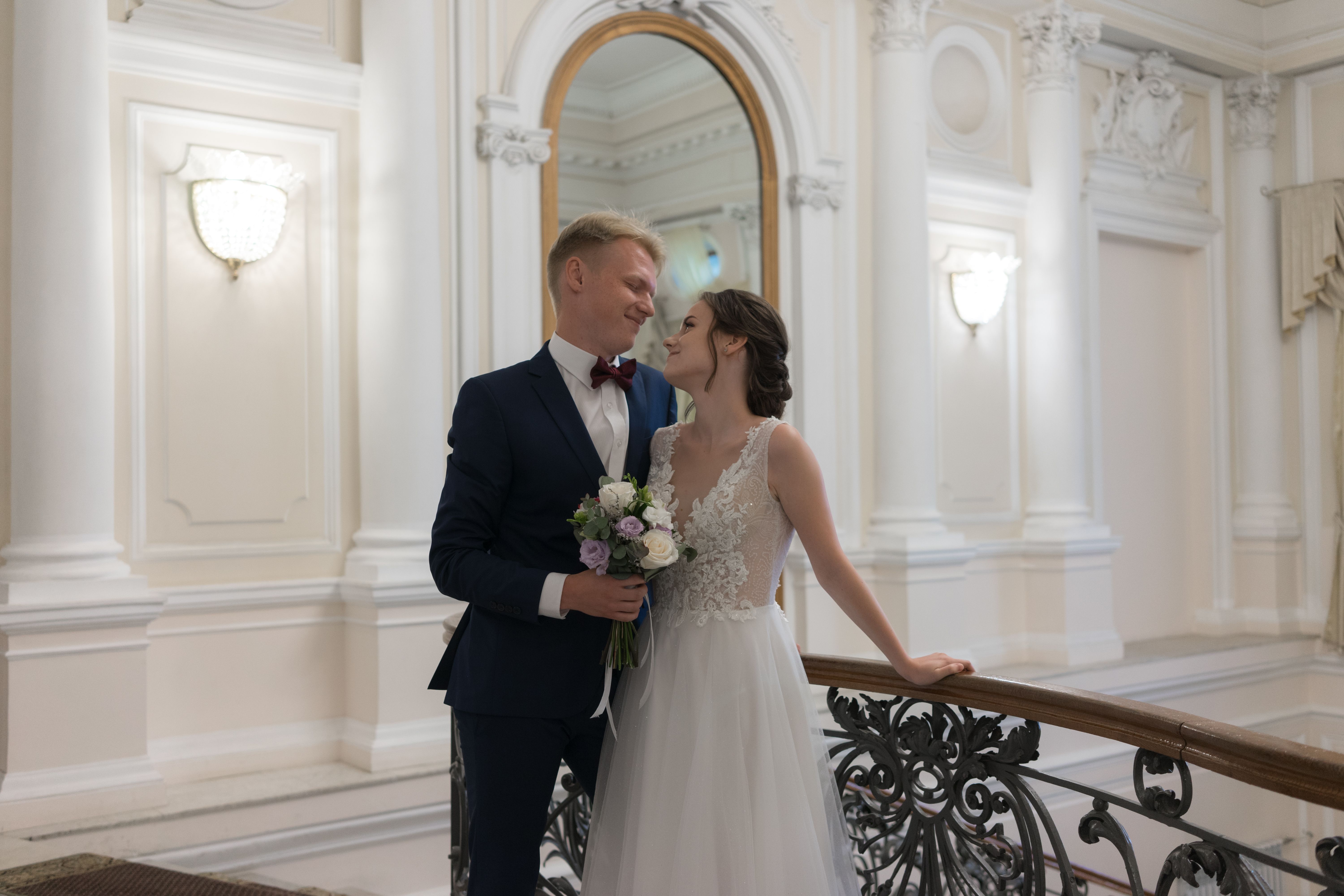 A newlywed couple shares a romantic moment in a beautifully decorated historic venue.
