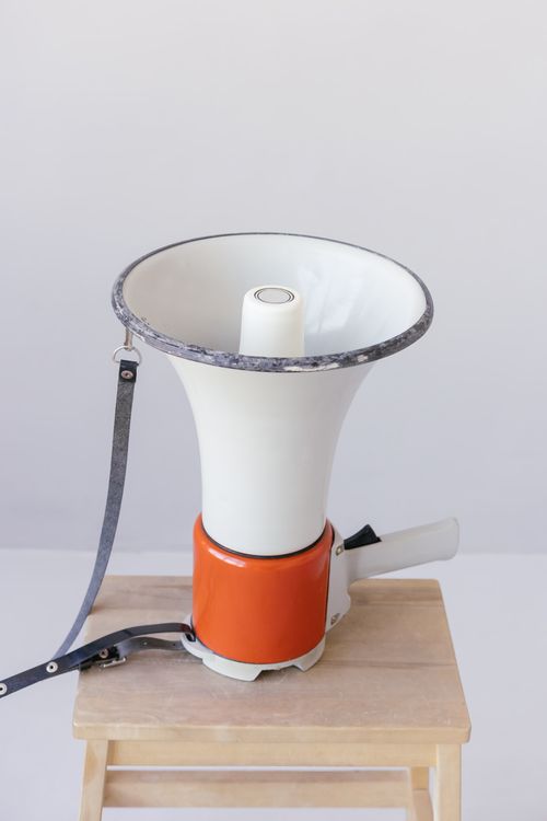 Free A classic megaphone rests on a simple wooden stool with neutral background. Stock Photo